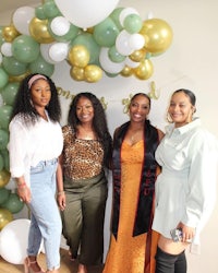 four women posing for a photo in front of balloons